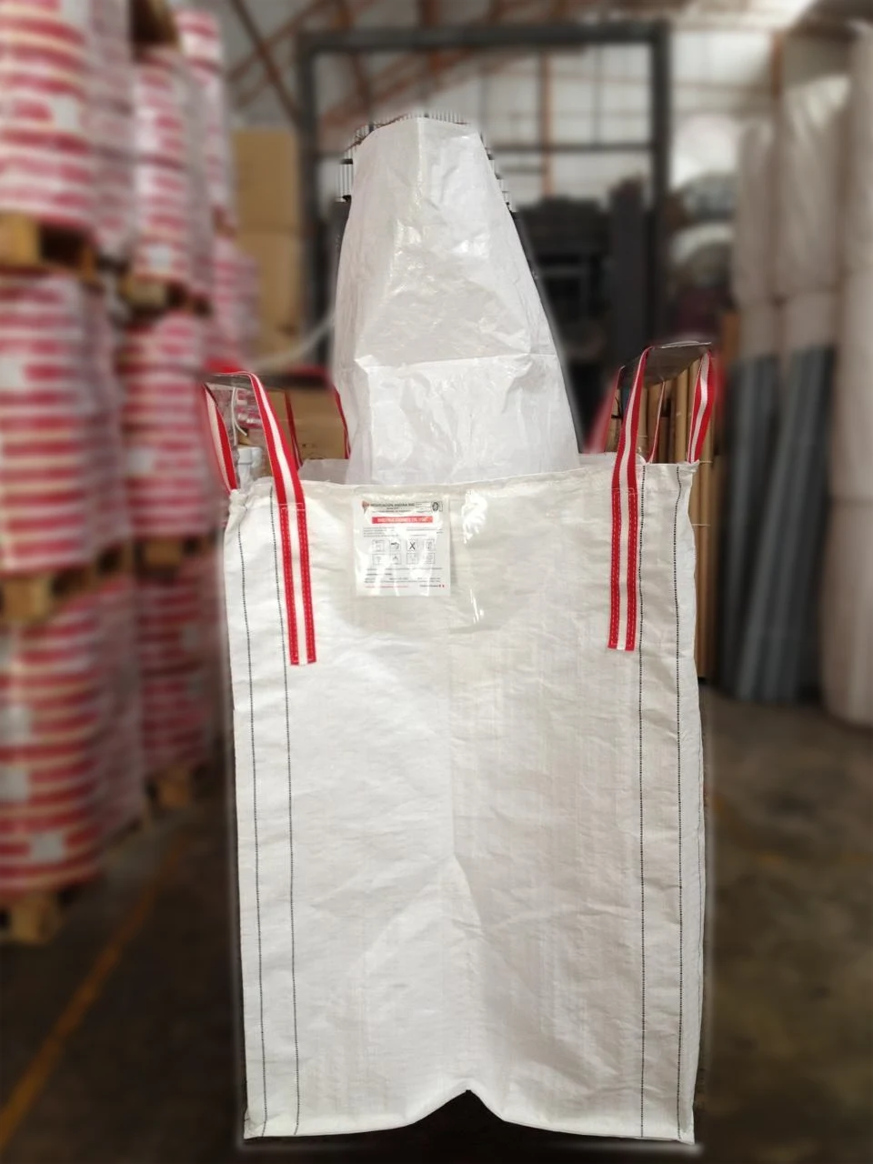 Finished NEGASAC Big Bag next to rolls of red and white webbing and polypropylene fabric